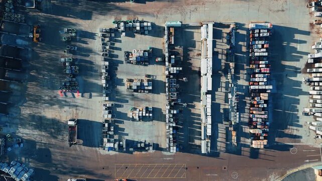 Rows of trucks and trailers fill the space below. Industrial chemical plant