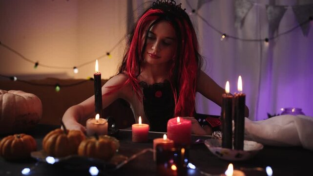 Cute Little Girl In A Halloween Witch Wig Plays With Candles Lighting Matches To Decorate The Room For A Party