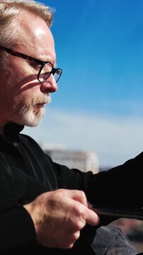 Concentrated male in black outfit sits ay window holding a laptop. Man in glasses checks e-mail and closes his gadget. Vertical video