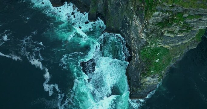 Aerial flight along Cliffs of Moher with waves crashing against sea cliffs, Ireland