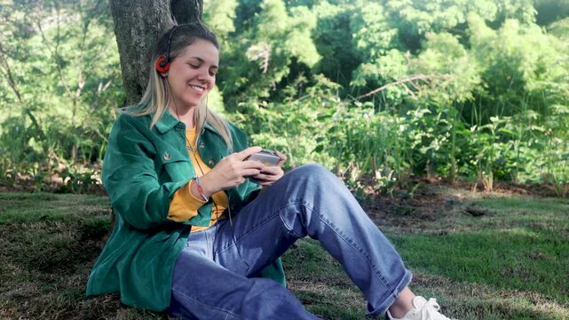 Happy woman listening music with vintage headphones and cassette radio player at park city - Nostalgia lifestyle trend