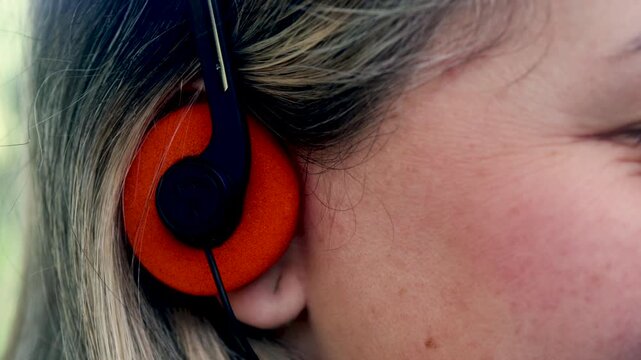 Close up of woman listening to music with vintage headphones outdoors - Nostalgia lifestyle trend