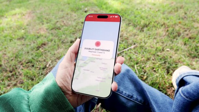 Person using earthquake app on mobile phone for real-time emergency alert - Venezuela doublet or twin quake magnitude warning