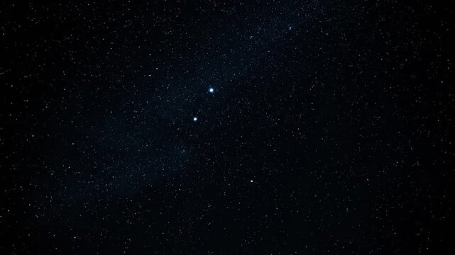 A wide view of a night sky with many stars, including a few brighter points of light