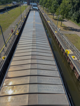 Gro&szlig;es Binnenschiff in einer Schleuse aus der Vogelperspektive, G&uuml;tertransport auf einer Wasserstra&szlig;e - Large inland cargo ship in a canal lock from a high angle view, freight transport on a waterway
