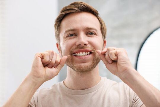 Man using dental floss indoors. Oral hygiene