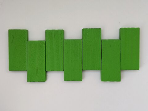 Abstract arrangement of green rectangular blocks forming rhythmic geometric pattern on white background.