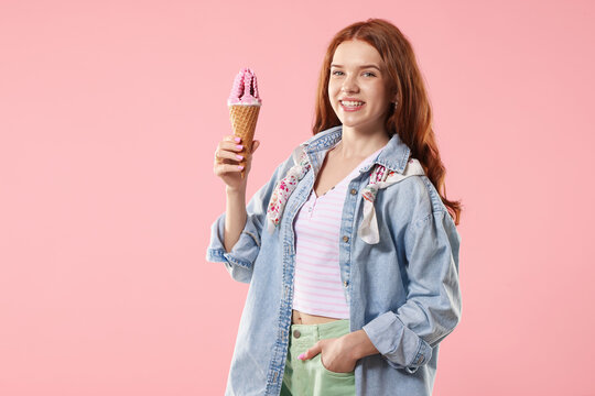 Happy teenage girl with delicious ice cream in waffle cone on pink background