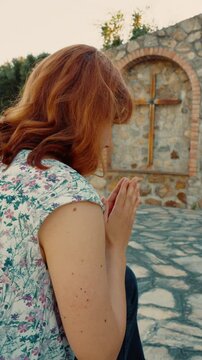 Woman prays at Calvary with outdoor crucifixes to ask for care of the sick
