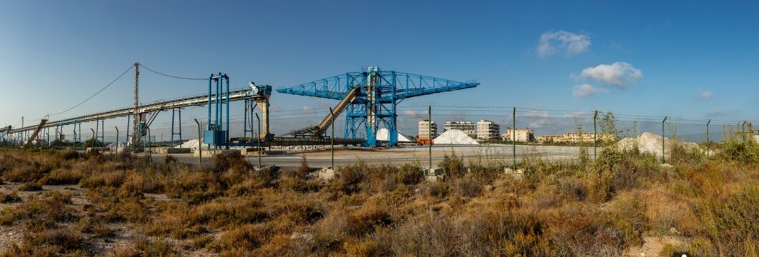 Wide view of an industrial salt production site in Santa Pola with machinery and piles of harvested sea salt