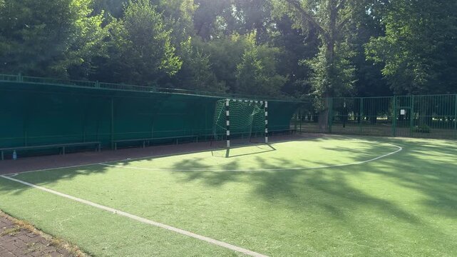 Empty artificial turf soccer field with green dugout and goal in a park. Outdoor sports ground, football pitch, summer recreation, leisure