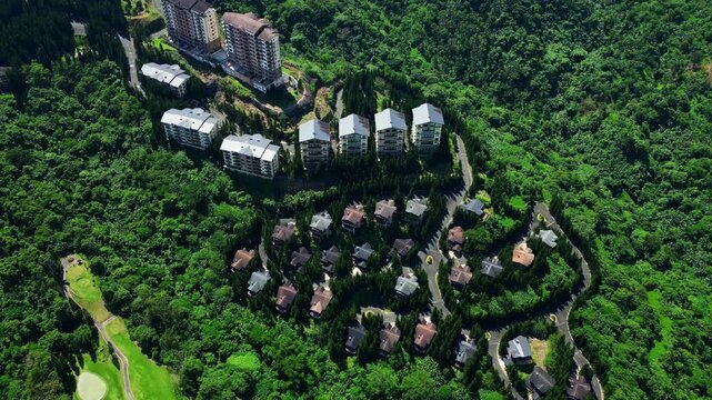 Slow pan drone footage across Woodridge Place highlighting luxury hospitality, mature trees, golf course landscaped open spaces, and scenic mountain environments at Tagaytay Cavite Philippines.