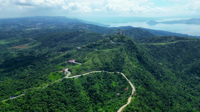 High altitude aerial footage showcasing panoramic mountain scenery, green forests, and winding roads surrounding People's Park in the Sky in Tagaytay Philippines.