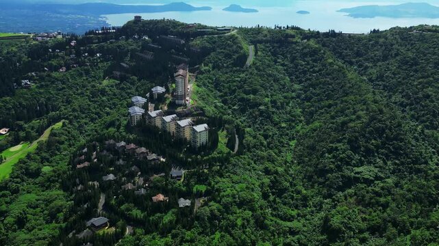 Atmospheric drone footage revealing beautifully maintained resort grounds, mature trees, and panoramic natural scenery surrounding Woodridge Place in Tagaytay City Cavite Philippines.