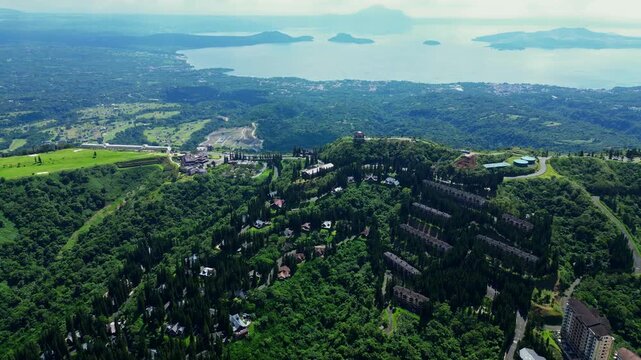 Smooth pullback drone reveal showcasing the luxury mountain resort community of Woodridge Place together with People's Park road overlooking Taal Lake and Taal Volcano.
