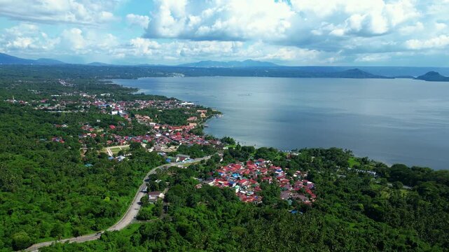 ide cinematic panorama featuring Talisay Residences framed by tropical greenery with Taal Lake stretching across the horizon.