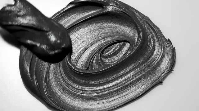 Charcoal face mask paste with metal spatula.