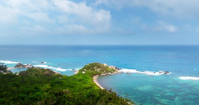 Green jungle and rocky coast with turquoise ocean waters in Tayrona National Park, Colombia. Aerial forward, copy space