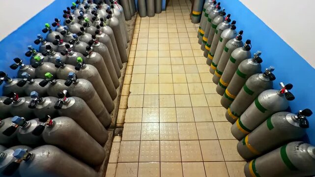 Rows of metal tanks organized in a tiled interior space, equipment storage concept.
