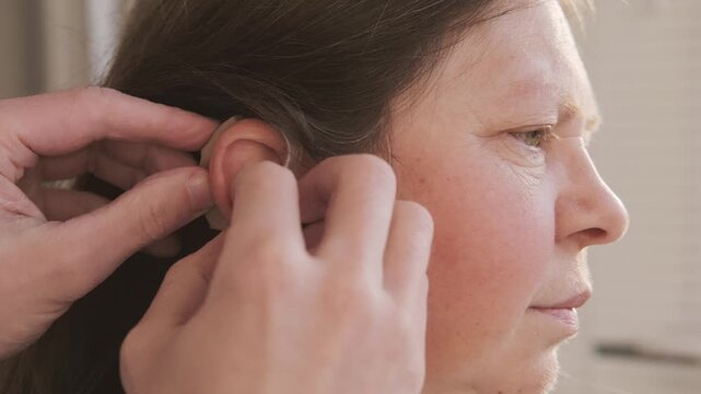 assistant fitting modern behind-the-ear hearing aidfemale ear, auditory perception, audiological hearing support, sound device, professional healthcare assistance, Technological progress ENT medicine