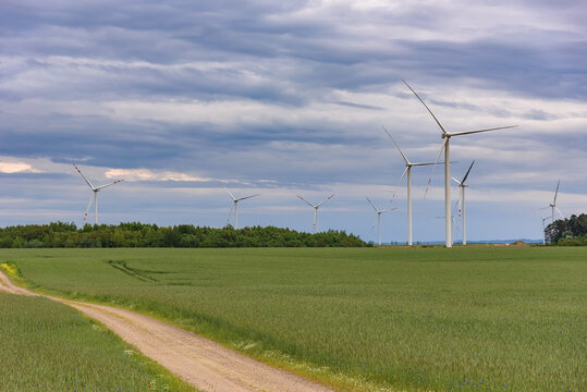 Wind turbines over a green field beneath dramatic clouds