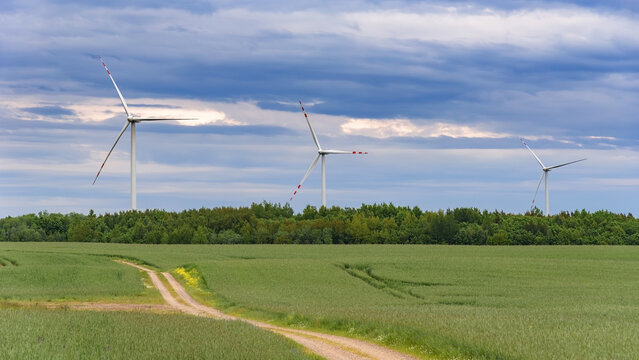 Wind turbines above rural fields under dramatic clouds