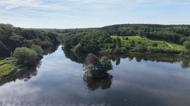 Aerial drone footage of river winding through woodland and countryside in Kirknewton near Edinburgh, Scotland. Scenic landscape featuring calm water, lush trees and cloudy sky