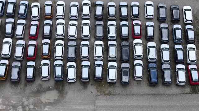 Finished crossover SUVs fill dense organized storage rows inside a major automotive logistics compound awaiting shipment, dealer allocation and wholesale distribution, drone pullback with parallax and
