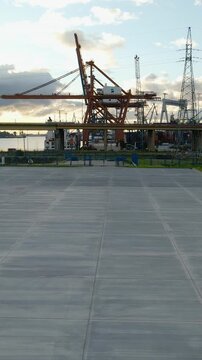A wide shot of the Gdynia mobile port featuring massive cargo cranes, the Estakada bridge, and industrial infrastructure under a golden hour sky.