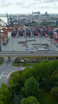 Cinematic aerial shot of a busy maritime container terminal in Gdynia, Poland, featuring cargo cranes, shipping containers, and traffic on the estakada bridge.