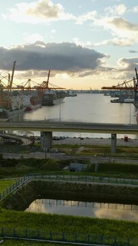 Cinematic aerial shot of the industrial port in Gdynia, Poland, featuring cargo ships, cranes, and the Estakada Kwiatkowskiego bridge during golden hour.