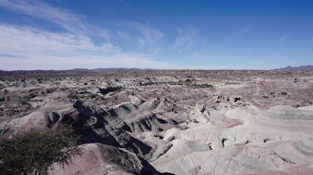 Eroded sedimentary badlands inside Ischigualasto Provincial Park, San Juan Province, Argentina, revealing arid desert landforms, ancient geological formations and deep ravines, drone yaw pan.Ischigual