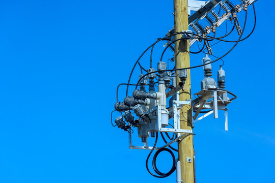 Power lines electrical equipment on utility pole in bright sky