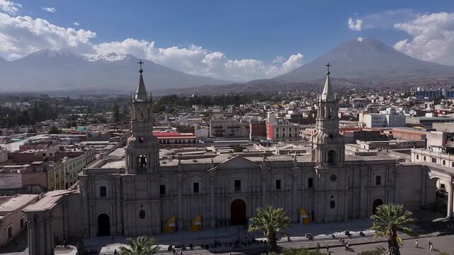 Aerial drone footage of the Basilica Cathedral of Arequipa with the iconic Misti volcano rising in the background. Historic colonial architecture overlooking the city center on a clear day in Arequipa