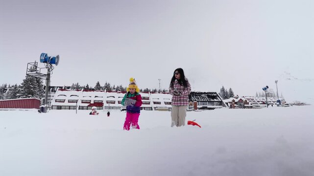 A mother and child have fun flinging snow while playing deep in the powder at the Las Le&ntilde;as ski resort in Mendoza, Argentina. Winter family vacation.