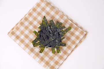 Fresh seaweed rests on a checkered cloth. Simple, clean background enhances the natural texture. Minimalist composition draws focus to the organic form. Ideal for health, wellness, or culinary themes © Nurma