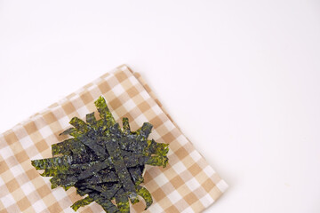 Fresh seaweed rests on a checkered cloth. Simple, clean background enhances the natural texture. Minimalist composition draws focus to the organic form. Ideal for health, wellness, or culinary themes © Nurma