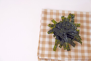 Fresh seaweed rests on a checkered cloth. Simple, clean background enhances the natural texture. Minimalist composition draws focus to the organic form. Ideal for health, wellness, or culinary themes © Nurma