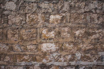 Fototapeta premium Textured stone wall surface with rustic brown blocks and aged mortar for architectural background
