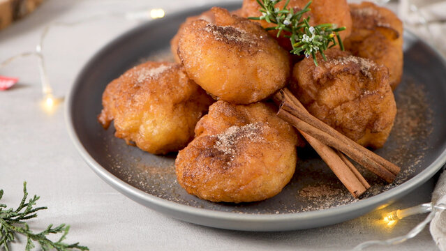 Fried dough fritters with cinnamon sugar on a grey plate