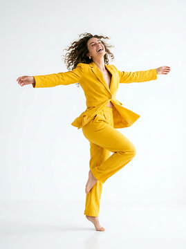 Joyful woman in a yellow suit dancing and having fun isolated on white background