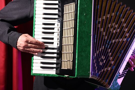 Man playing piano accordion on stage, closeup