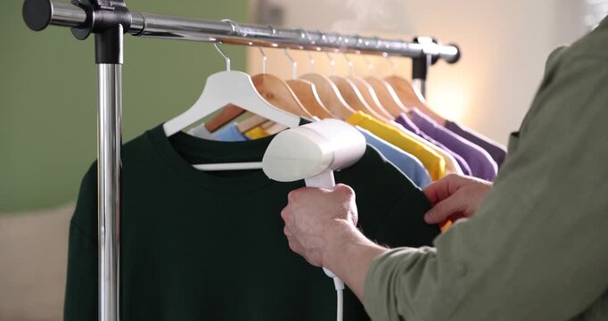 Man steaming t=shirt with modern steamer at home, closeup