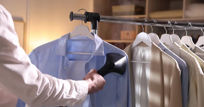 Man steaming shirt with upright steamer at home, closeup