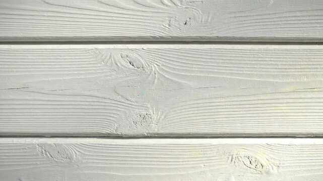 Close up view of painted white wood siding on an exterior building wall with natural wood grain and knots