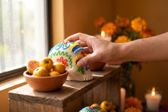 Close-up of a hand placing a traditional sugar skull for Dia de Muertos.