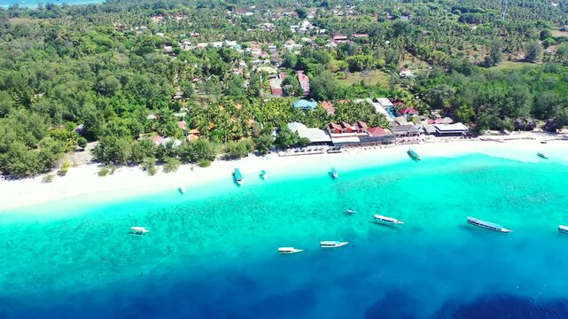 Aerial view of gili meno island with boats floating on clear turquoise water near white sand beach and tropical trees.