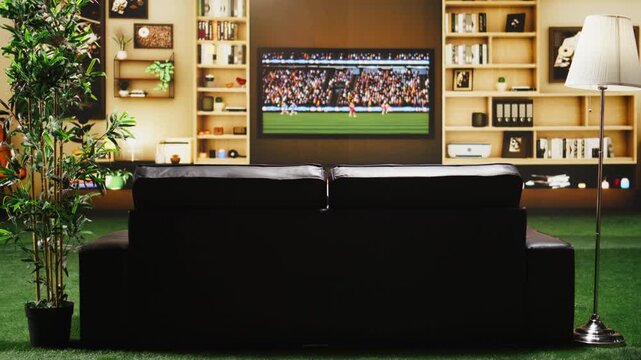 Soccer broadcast plays on a TV screen left on in an empty apartment living room, with a sofa ready for weekend match viewing during a home watch party.