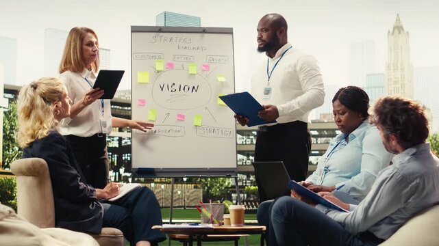 Diverse planning team presenting roadmap ideas on vision board, discussing business strategy on whiteboard during meeting, urban terrace presentation.