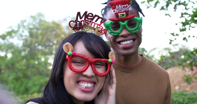 African American man and Asian woman couple posing, laughing, adjusting novelty glasses for camera